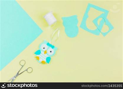 overhead view paper owl with thread spool scissor yellow background