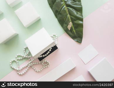 overhead view pearl necklace golden earrings with white boxes paper background