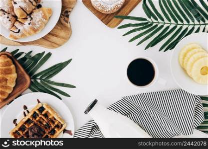 overhead view pineapple slices baked croissant waffles buns tortillas milk bottle coffee white backdrop
