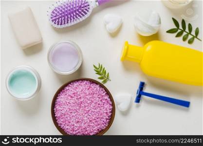 overhead view pink salt with cosmetics products white background