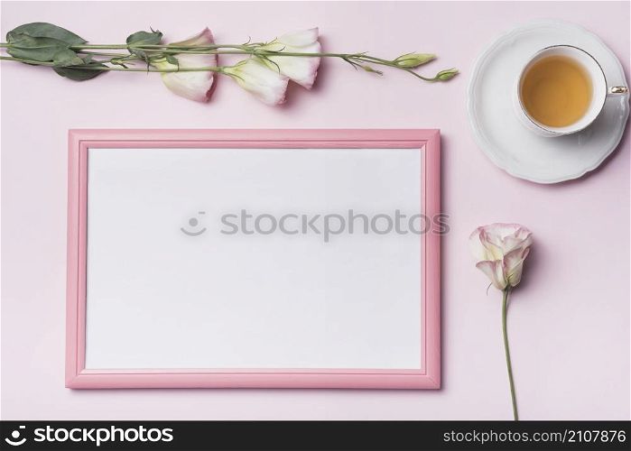 overhead view tea cup with picture frame eustoma flowers against pink background