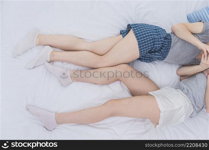 overhead view two lesbian couple lying white bed