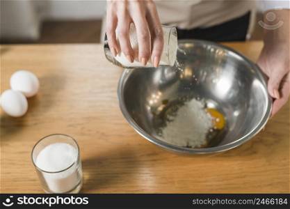 overhead view woman pouring flour utensil wooden table