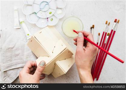 overhead view woman s hand painting wooden house model with paintbrush