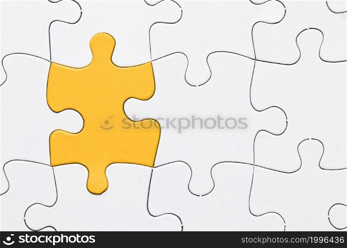 overhead view yellow puzzle among white piece