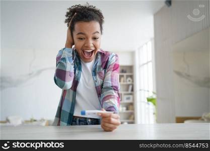 Overjoyed african american teen girl looks at her body temperature on thermometer at home. Emotional biracial young woman feel happy, has no covid coronavirus symptoms. Healthcare concept. Overjoyed african american teen girl check body temperature with thermometer, has no covid symptom