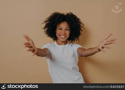 Overjoyed African woman in 20s, arms wide open, inviting hug. Positive energy.