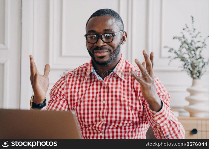 Overjoyed afro american businessman in glasses reading great news on laptop at workplace, happy african man employee receiving email, celebrating business success while sitting at office desk. Overjoyed afro american businessman in glasses reading great news on laptop at workplace