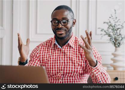 Overjoyed afro american businessman in glasses reading great news on laptop at workplace, happy african man employee receiving email, celebrating business success while sitting at office desk. Overjoyed afro american businessman in glasses reading great news on laptop at workplace