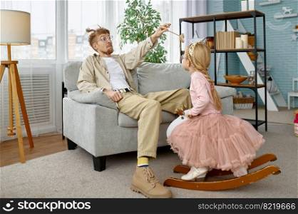 Overjoyed father with funny appearance and cute daughter spending time together at home. Overjoyed father and daughter spending time together