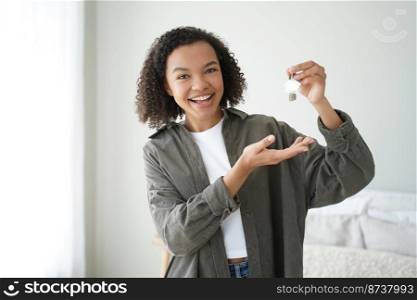 Overjoyed mixed race young female tenant holding house keys excited moving in new apartment. Smiling teen girl renter happy with relocating and buying first own home. Rental, tenancy concept.. Joyful mixed race girl tenant holding keys to new home, happy with relocating to first own apartment