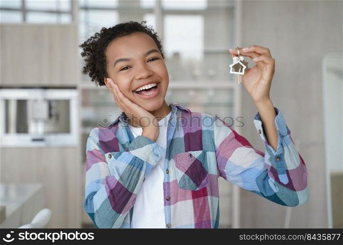 Overjoyed young african american lady is holding key from new apartment. Happy teenage girl rents her first home. Mortgage loan, real estate purchase and relocation conceptual image.. Overjoyed young african american lady is holding key from new apartment. Real estate purchase.