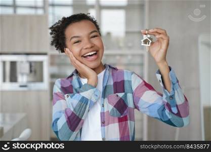 Overjoyed young african american lady is holding key from new apartment. Happy teenage girl rents her first home. Mortgage loan, real estate purchase and relocation conceptual image.. Overjoyed young african american lady is holding key from new apartment. Real estate purchase.