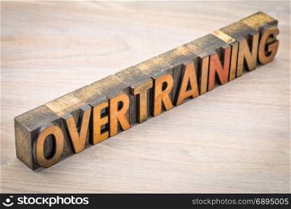 overtraining word abstract in vintage letterpress wood type against grained wood