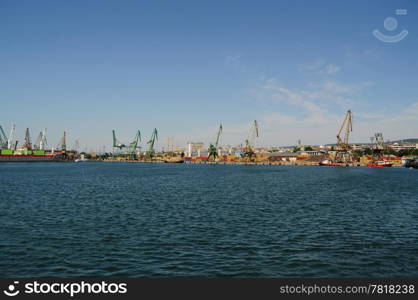 Overview of stacked containers and cranes at harbour