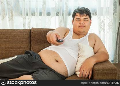 Overweight guy sitting on the couch to watch some TV