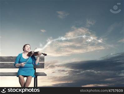 Overweight problem. Middle aged stout woman in blue dress sitting on bench and playing violin