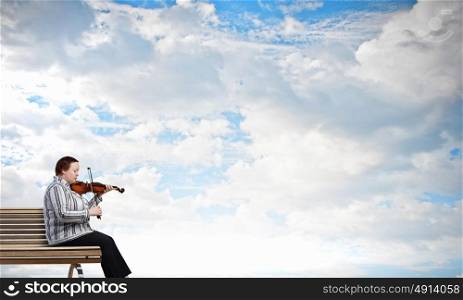 Overweight problem. Middle aged stout woman sitting on bench and playing violin