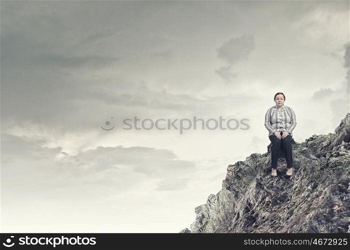 Overweight problem. Middle aged stout woman sitting on rock top