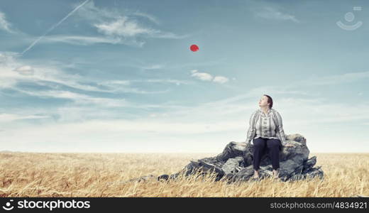 Overweight problem. Middle aged stout woman sitting on rock top