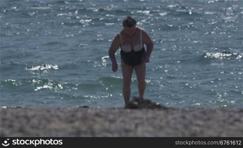 Overweight senior woman in swimsuit after swimming on the beach