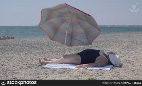 Overweight senior woman lying on the beach