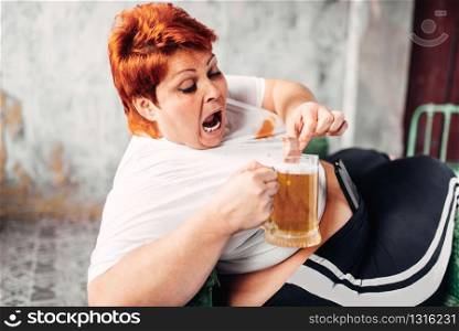 Overweight woman drinks beer and eats sandwich, bulimic, obesity. Unhealthy lifestyle, fatty female. Overweight woman drinks beer, obesity