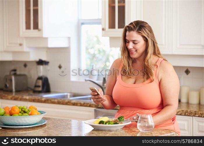 Overweight Woman Eating Healthy Meal And Using Mobile Phone