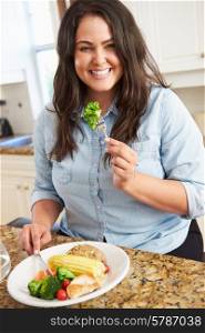 Overweight Woman Eating Healthy Meal In Kitchen