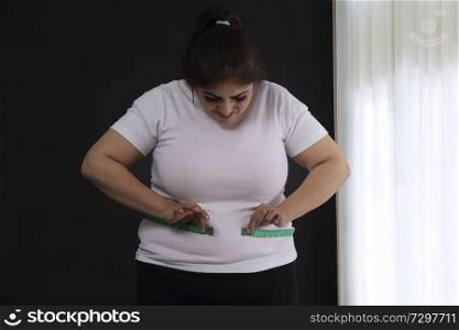 Overweight woman measuring her waist with a tape measure