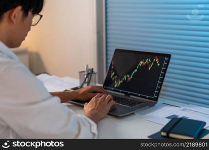 Overwork Concept The office employee working at the office by analyzing the graph on his laptop screen.