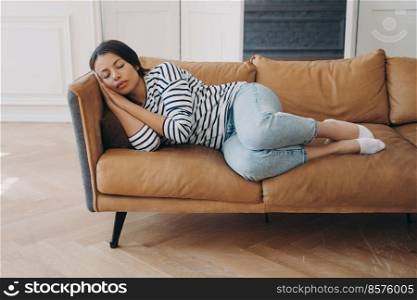Overworked female sleeping lying on comfortable sofa in living room, resting after hard work day. Tired woman fall asleep on couch at home, takes day nap after party sleepless night. Fatigue concept.. Tired female sleeping lying on comfortable cozy couch, napping, enjoy recreation after hard work day