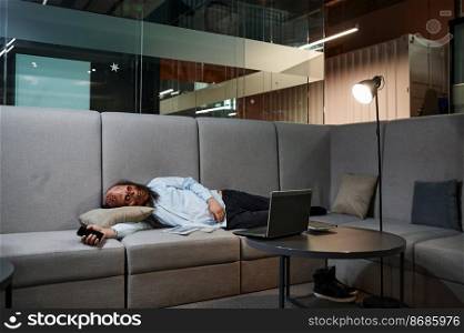 Overworked zombie employee sleeping on sofa couch in office. Tired executive manager resting feeling tired. Overworked zombie sleeping on sofa in office
