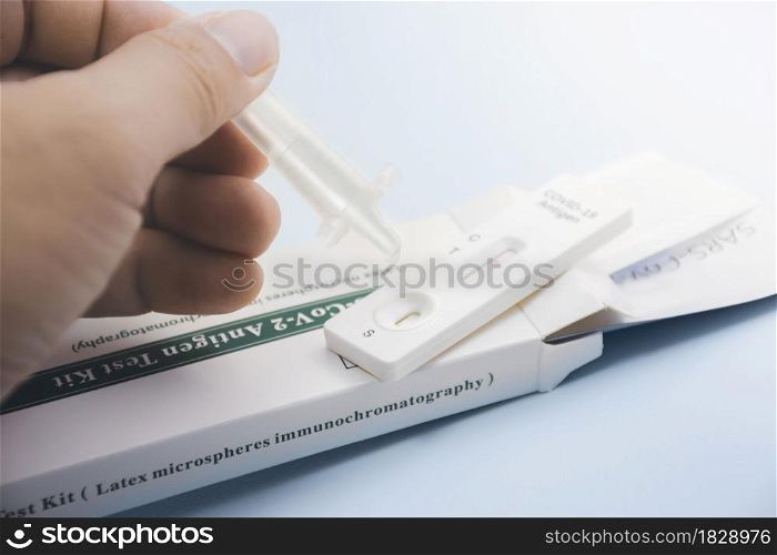 Own hand placing the secretions sample into the SARS CoV-2 Rapid antigen test kit (ATK) with the extraction tube,Coronavirus infectious protective concept
