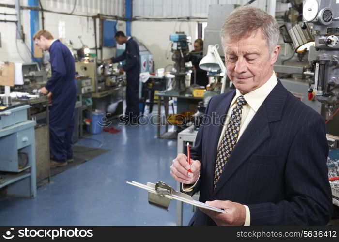 Owner Of Engineering Factory With Staff In Background