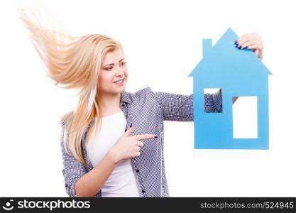 Ownership and property concept. Happy woman with windblown hair holding blue paper house, moving to new home.. Happy woman holding blue paper house