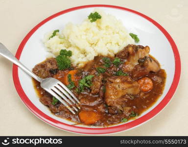 Oxtail stew, a very old British dish, on a plate with mashed potato and a fork