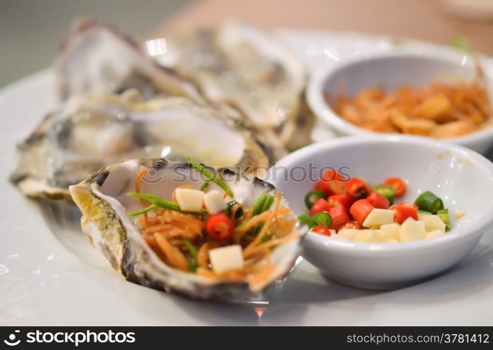 Oysters with chili and fried garlic , on white plate