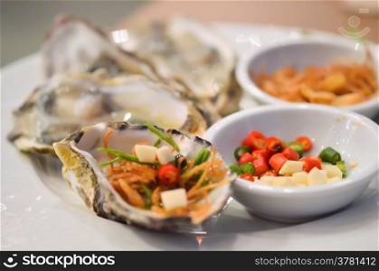 Oysters with chili and fried garlic , on white plate