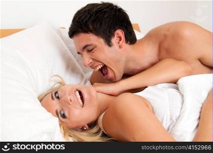 Paar hat Spass im Bett. Lachen, Freude und Erotik im Schlafzimmer