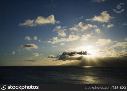 Pacific ocean and island with sun streaming through clouds.