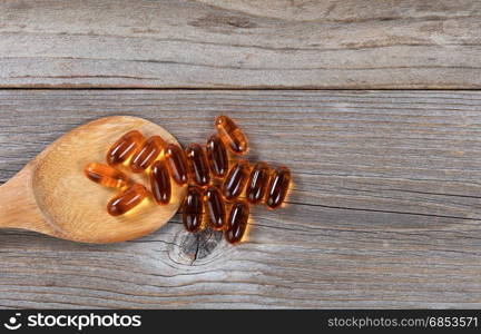 Pacific salmon fish oil capsules and wooden spoon on rustic wood. Flat lay view.