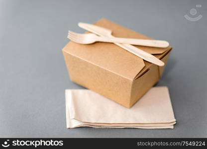 package, recycling and eating concept - disposable box for takeaway food with wooden fork, knife and napkin on table. disposable paper box for takeaway food