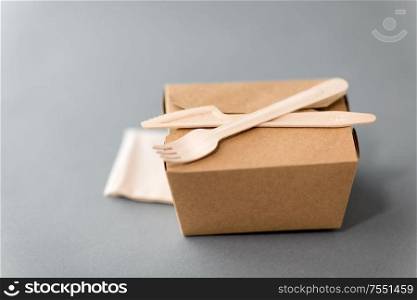 package, recycling and eating concept - disposable box for takeaway food with wooden fork, knife and napkin on table. disposable paper box for takeaway food