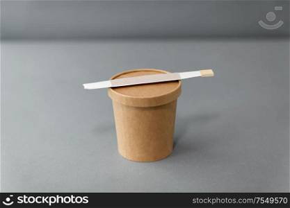 package, recycling and eating concept - disposable paper container for takeaway food or wok with chopsticks on table. paper container for takeaway food with chopsticks