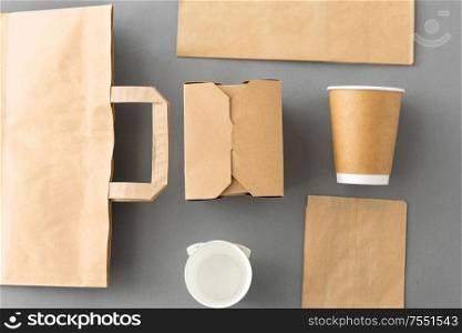 package, recycling and eating concept - disposable paper container for takeaway food, coffee cups and bags on grey background. disposable paper takeaway food packing stuff