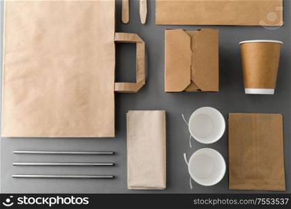 package, recycling and eating concept - disposable paper container for takeaway food with cups, bags, napkins and cutlery on table. disposable paper takeaway food packing stuff