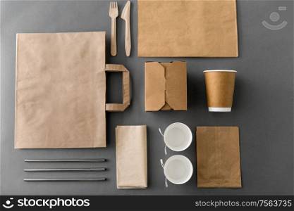 package, recycling and eating concept - disposable paper container for takeaway food with cups, bags, napkins and cutlery on table. disposable paper takeaway food packing stuff