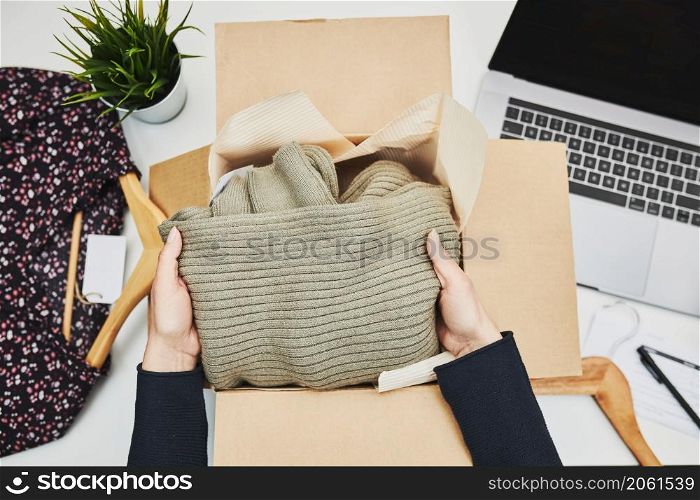 Packing online order to delivery to customer. Preparing parcel box with clothes product from online shop