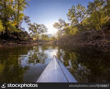paddling kayak on mountain lake against a low sun - Horsetooth Reservoir in northern Colorado in fall scenery